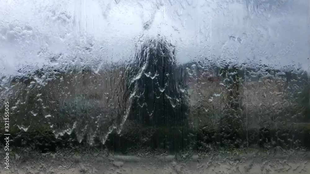 From a window of a car you can see the rain falling on the glass and the blurred background is a building, storm or thunderstorm. From a window of a car you can see the rain falling on the glass and the blurred background is a building, storm or thunderstorm.