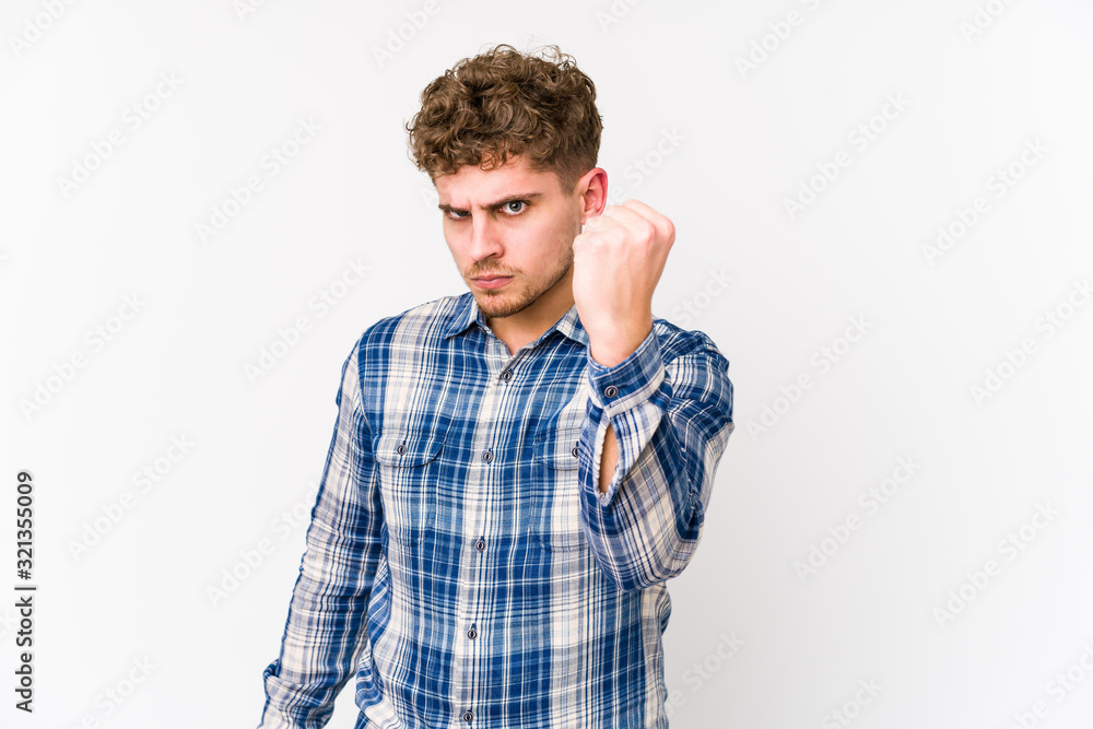 Young blond curly hair caucasian man isolated showing fist to camera, aggressive facial expression. Young blond curly hair caucasian man isolated showing fist to camera, aggressive facial expression.