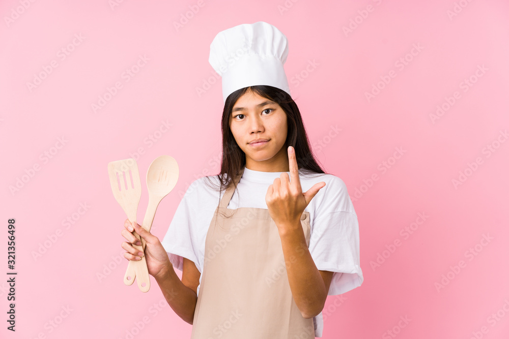 Young chinese chef woman isolated pointing with finger at you as if inviting come closer. Young chinese chef woman isolated pointing with finger at you as if inviting come closer.
