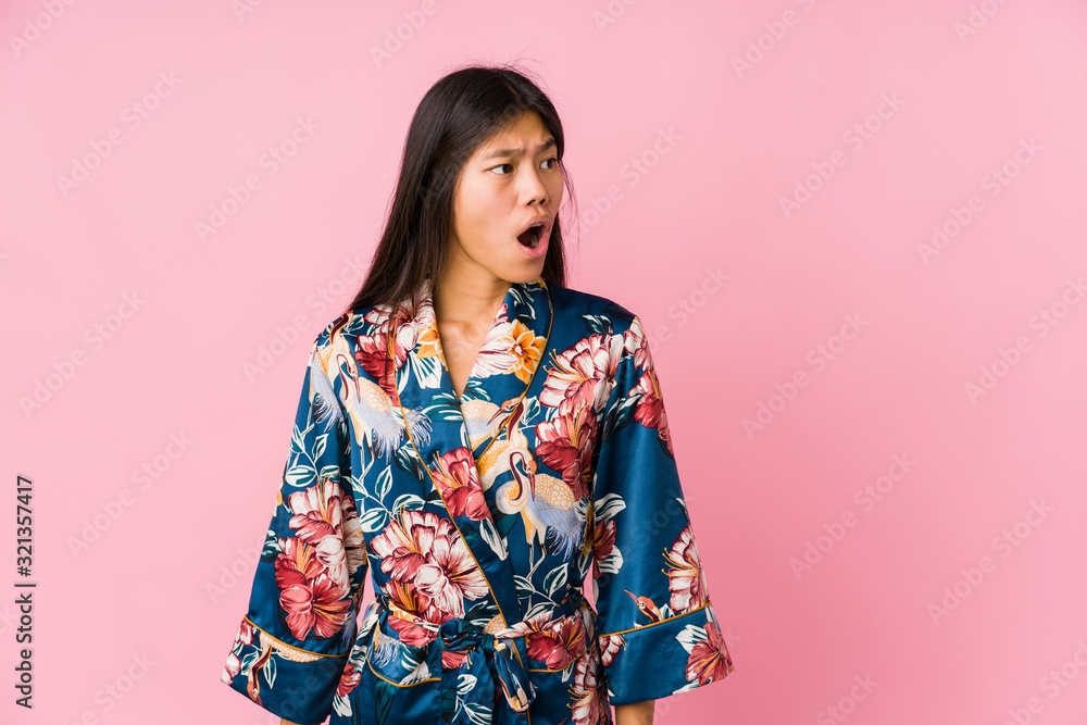 Young asian woman wearing a kimono pajamas being shocked because of something she has seen. Young asian woman wearing a kimono pajamas being shocked because of something she has seen.