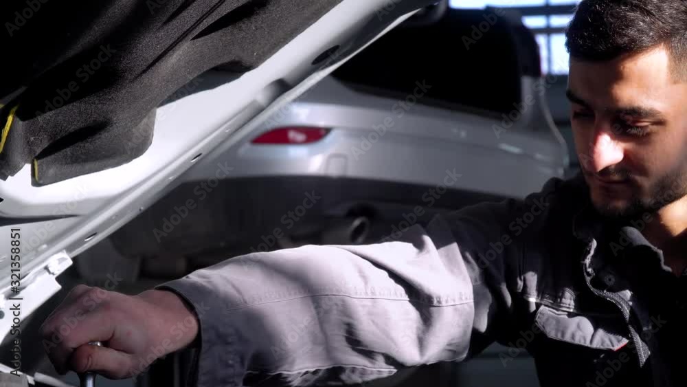 Professional mechanic repairing a car in car repair shop. Car service, repair and maintenance Professional mechanic repairing a car in car repair shop. Car service, repair and maintenance