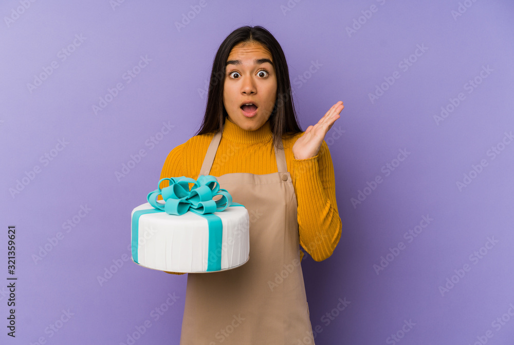 Young asian woman holding a cake isolated surprised and shocked. Young asian woman holding a cake isolated surprised and shocked.