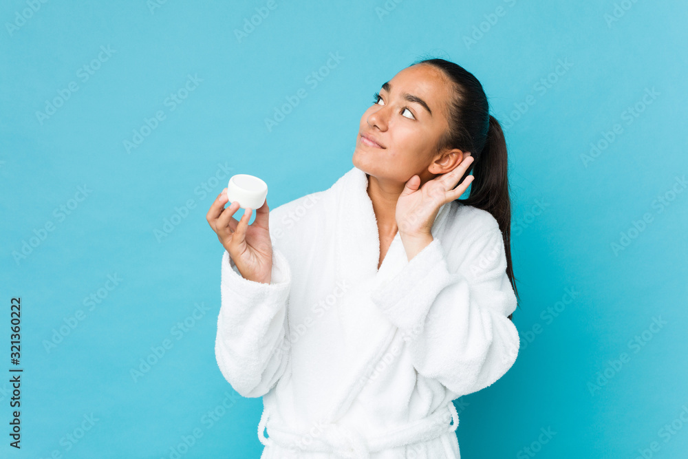 Young mixed race indian holding a moisturizer trying to listening a gossip. Young mixed race indian holding a moisturizer trying to listening a gossip.