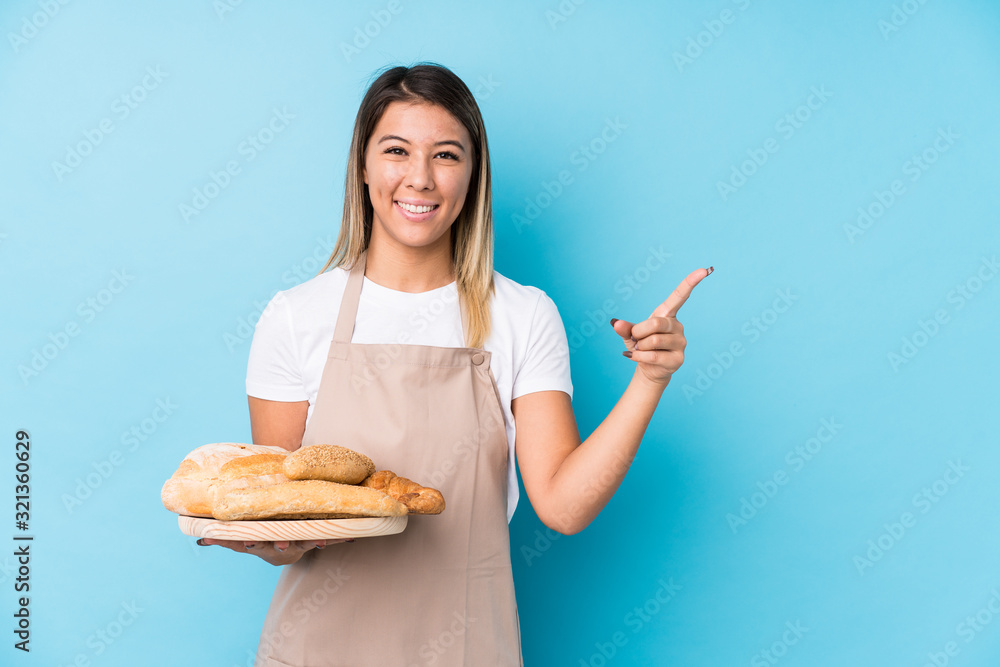 Young caucasian baker woman isolated smiling and pointing aside, showing something at blank space. Young caucasian baker woman isolated smiling and pointing aside, showing something at blank space.