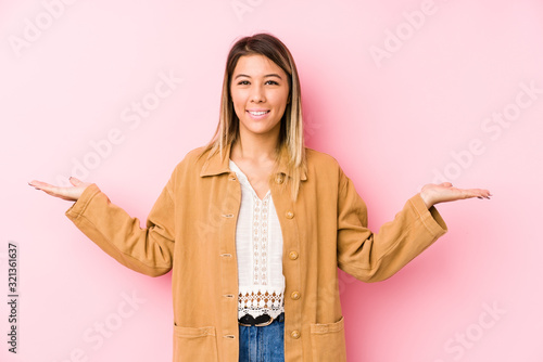 young caucasian woman posing isolated makes scale with arms, feels happy and confident.