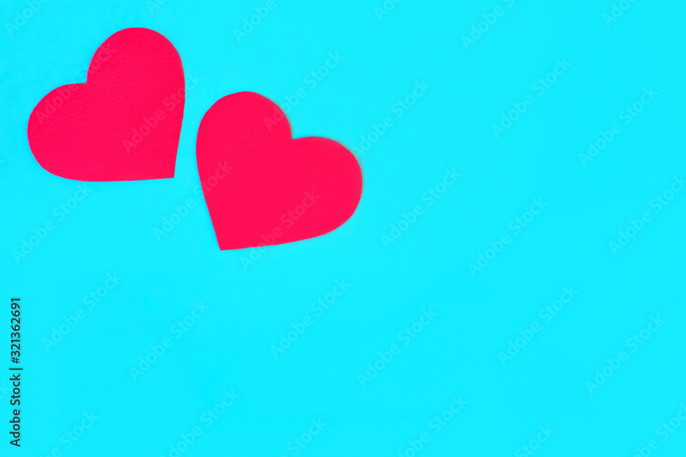 Two red, paper hearts on a blue background, place for text Two red, paper hearts on a blue background, place for text