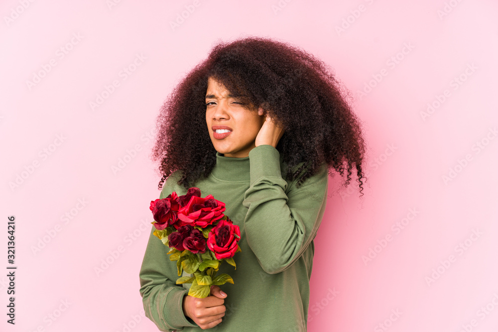 Young afro woman holding a roses isolated Young afro woman holding a rosescovering ears with hands. Young afro woman holding a roses isolated Young afro woman holding a rosescovering ears with hands.