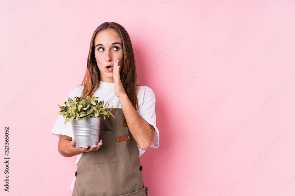 Young gardener caucasian woman isolated is saying a secret hot braking news and looking aside Young gardener caucasian woman isolated is saying a secret hot braking news and looking aside