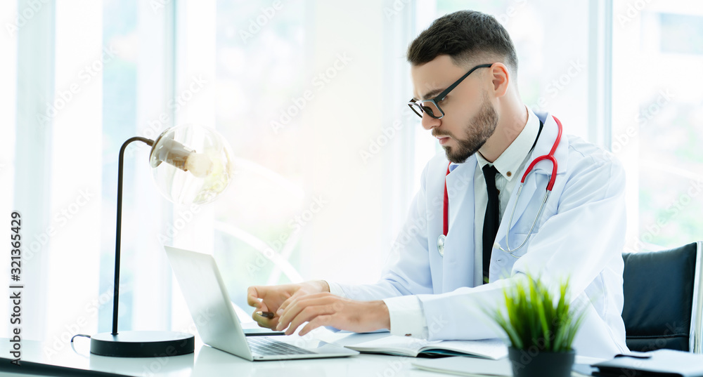 Portrait of Caucasian man doctor looking for treatment information using laptop in hospital room or clinic. Providing patients with care and willingness And quality expertise. Health insurance concept