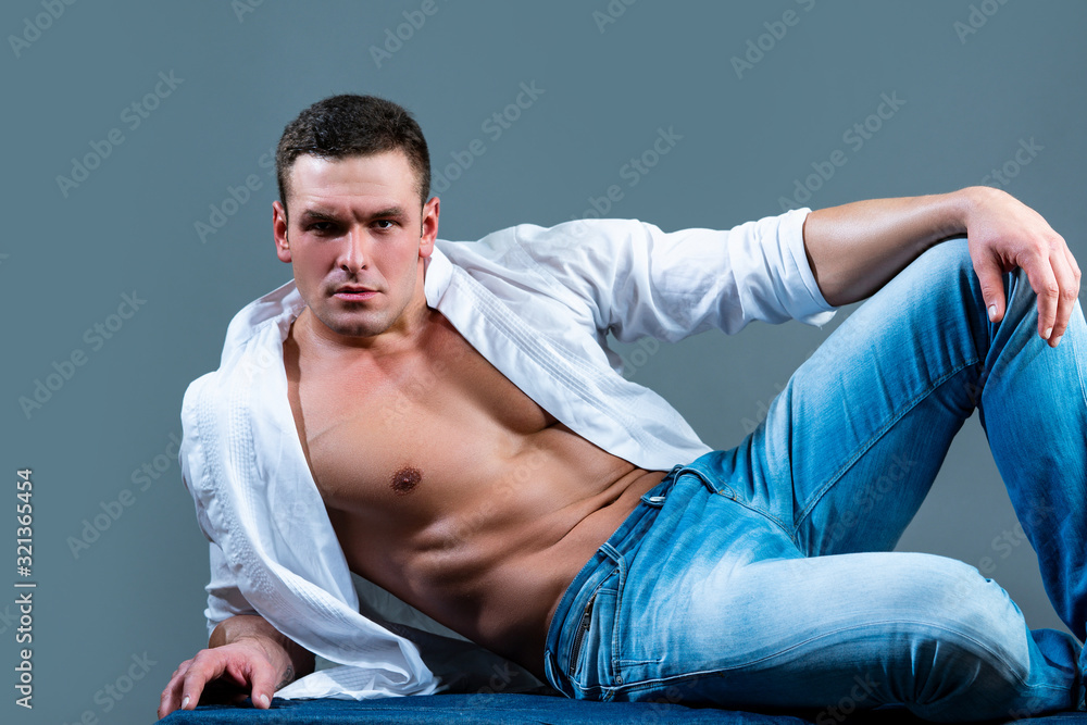 Muscular male in jeans. Sexy muscular man in white shirt and blue jeans.  Male clothes. Man in jeans on gray background. Stock Photo | Adobe Stock