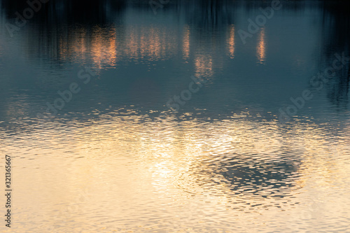 Reflections in lake water at sunset. Evening sky reflected in water.