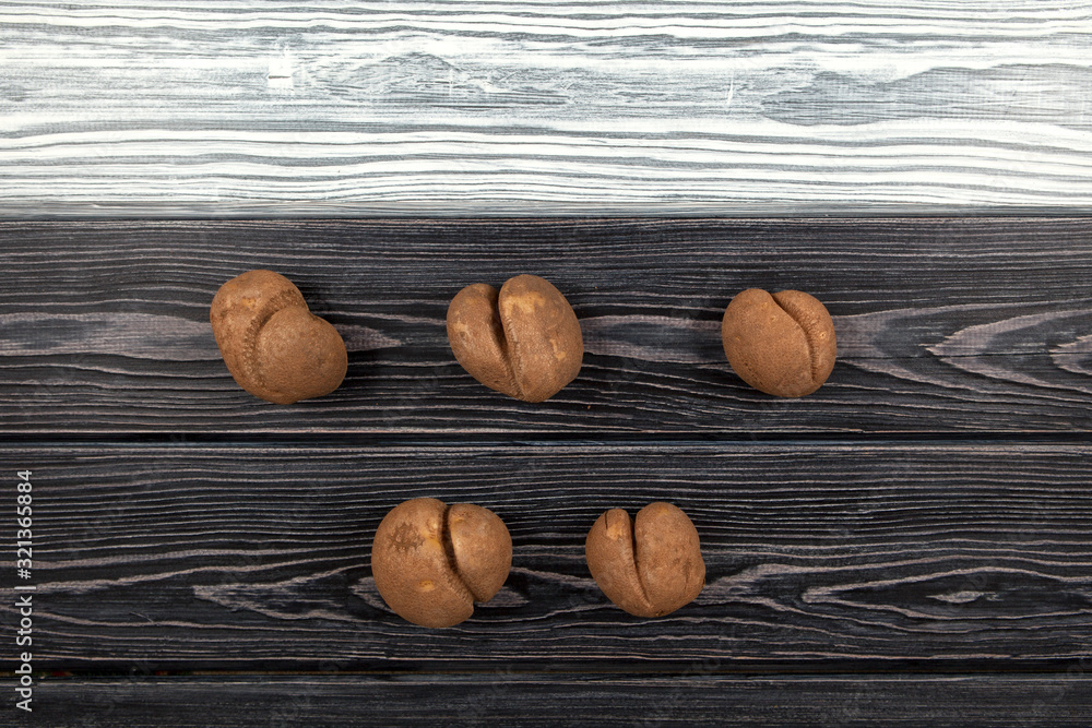 Vegetables of a funny form. Five ugly potatoes on a black and white wooden background. Top view. Vegetables of a funny form. Five ugly potatoes on a black and white wooden background. Top view.