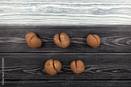 Vegetables of a funny form. Five ugly potatoes on a black and white wooden background. Top view.