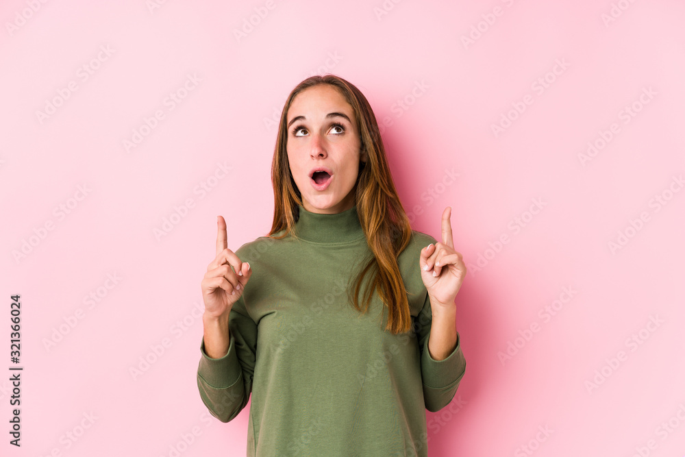 Young caucasian woman posing isolated pointing upside with opened mouth. Young caucasian woman posing isolated pointing upside with opened mouth.