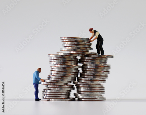 Two miniature men stacking coins. photo