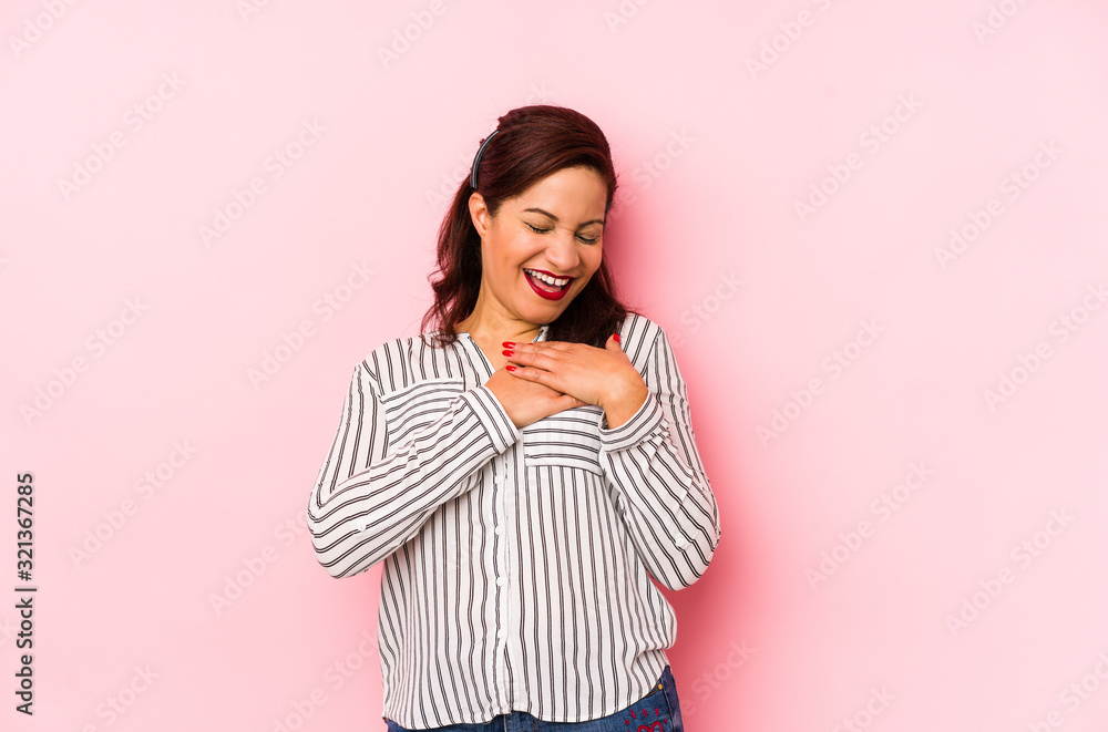 Middle age latin woman isolated on a pink background laughing keeping hands on heart, concept of happiness. Middle age latin woman isolated on a pink background laughing keeping hands on heart, concept of happiness.