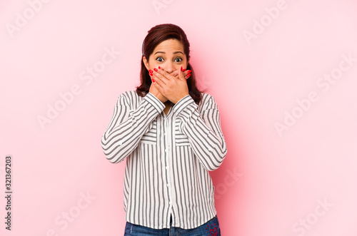 Middle age latin woman isolated on a pink background shocked covering mouth with hands. © Asier