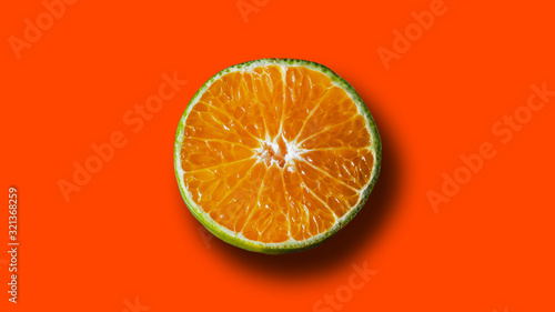 Single orange split isolated in brigh lush lava color background. Trendy wallpaper of fruit.
