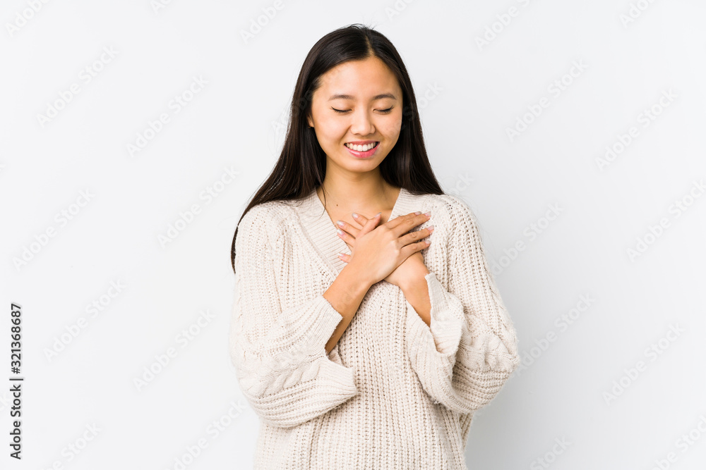 Young chinese woman isolated laughing keeping hands on heart, concept of happiness. Young chinese woman isolated laughing keeping hands on heart, concept of happiness.