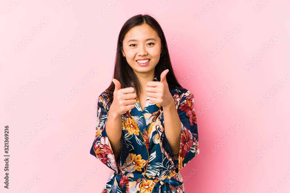 Young chinese woman wearing a kimono pajama isolated with thumbs ups, cheers about something, support and respect concept. Young chinese woman wearing a kimono pajama isolated with thumbs ups, cheers about something, support and respect concept.