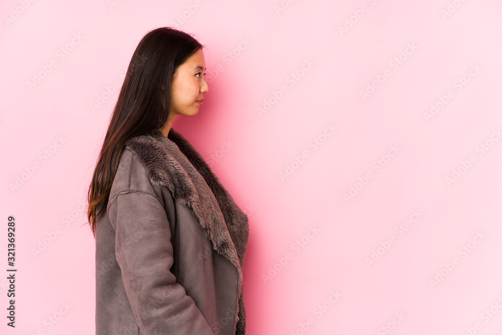 Young chinese woman wearing a coat isolated gazing left, sideways pose. Young chinese woman wearing a coat isolated gazing left, sideways pose.