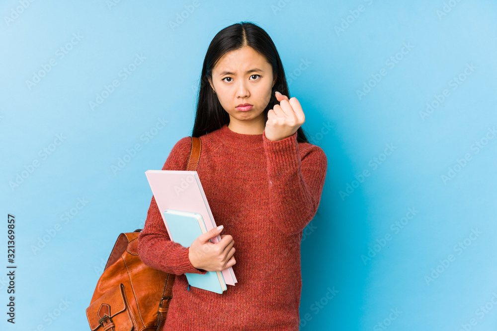 Obraz premium Young chinese student woman isolated showing fist to camera, aggressive facial expression.