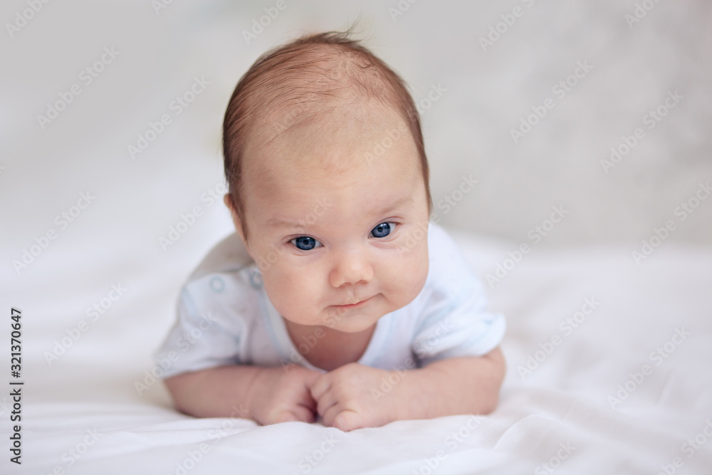 baby, newborn baby, cute blue-eyed, dark hair, baby 1 month, lying on a white bed