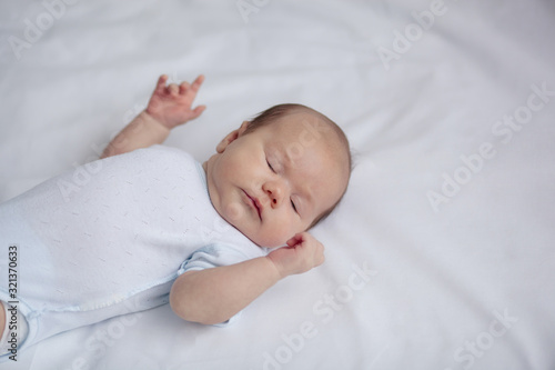 baby, newborn baby, cute blue-eyed, dark hair, baby 1 month, lying on a white bed