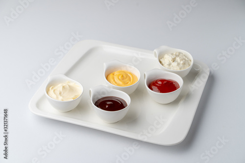 Set of assorted snack sauces isolated on white background: sour cream, mayo, mustard, ketchup and bbq sauce
