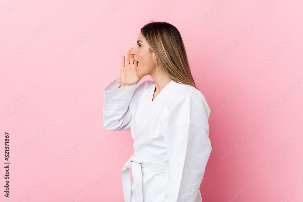 Young karate woman shouting and holding palm near opened mouth. Young karate woman shouting and holding palm near opened mouth.