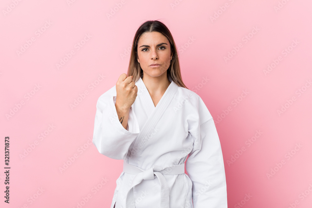 Young karate woman showing fist to camera, aggressive facial expression. Young karate woman showing fist to camera, aggressive facial expression.