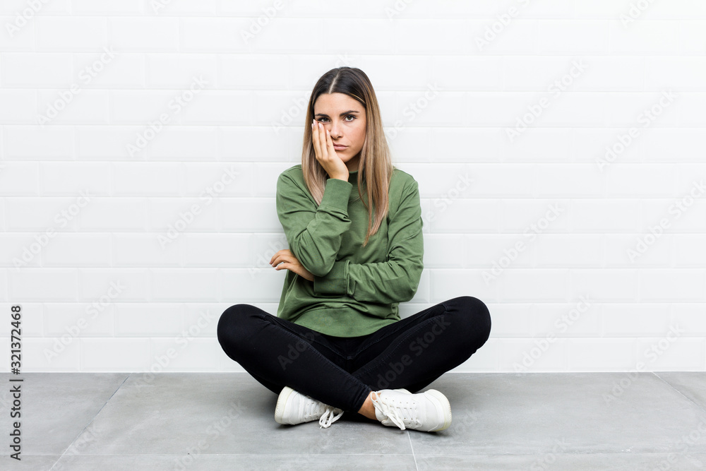 Young caucasian woman sitting on the floor who is bored, fatigued and need a relax day. Young caucasian woman sitting on the floor who is bored, fatigued and need a relax day.