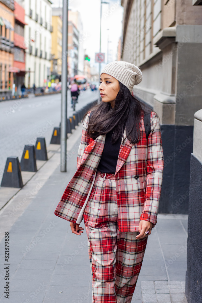 Fototapeta premium attractive woman walking down the street wearing a plaid suit and a hat