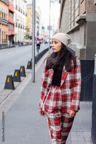 fashionable woman walking down the street wearing a plaid suit and a hat