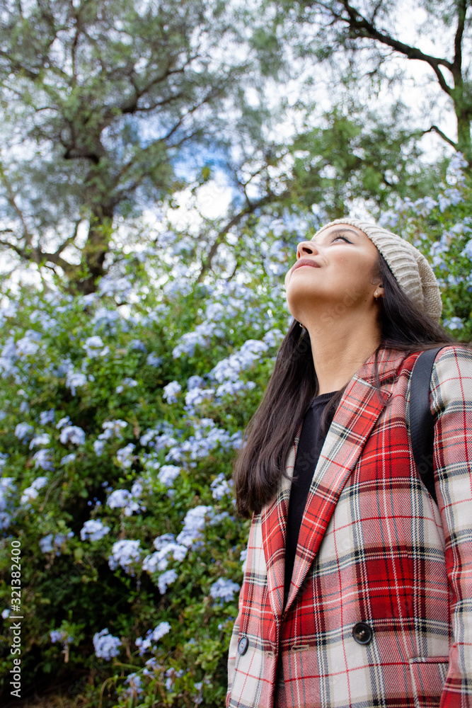 Pretty young woman wearing a red plaid suit in a green and flowered garden Pretty young woman wearing a red plaid suit in a green and flowered garden