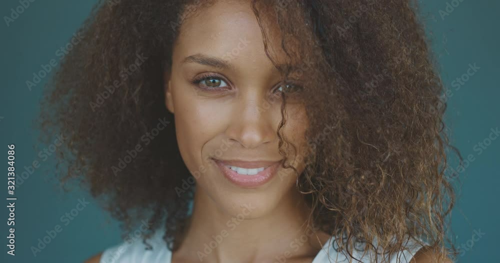 Portrait of a happy carefree african american woman smiling in front of a blue seamless background, black fashion model smiling for the camera