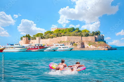 Girls in bikini lying on air bed - Pigeon Island with a "Pirate castle". Kusadasi harbor, Aegean coast of Turkey.