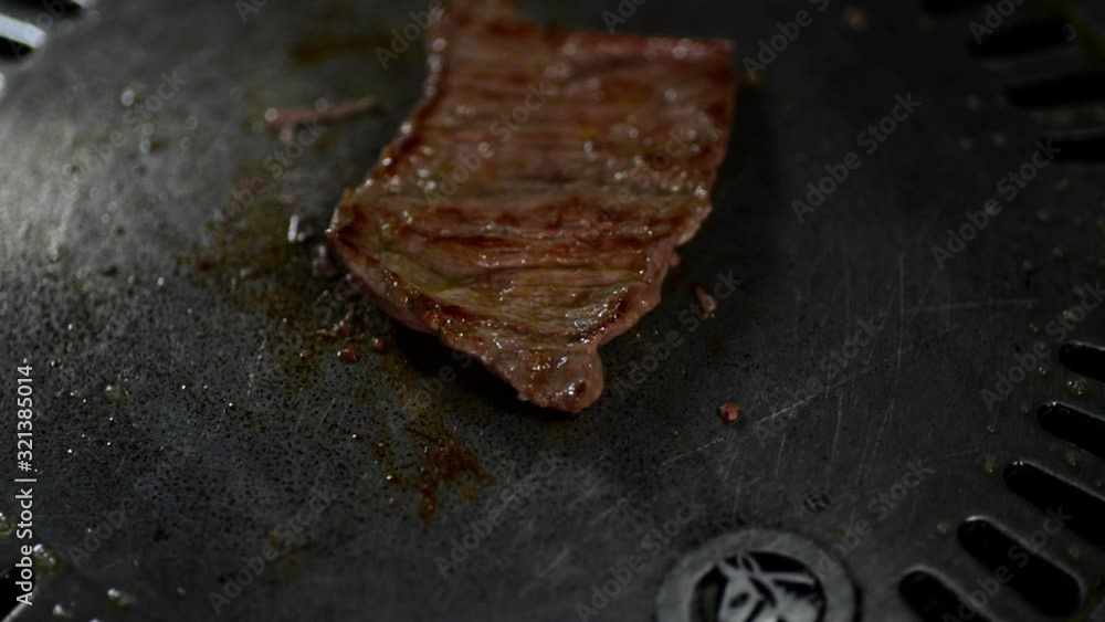 A Piece Of Delicious Barbecue Meat Grilled Over A Grilling Pan Turning Over With Tongs In Cambodia - Closeup Shot A Piece Of Delicious Barbecue Meat Grilled Over A Grilling Pan Turning Over With Tongs In Cambodia - Closeup Shot