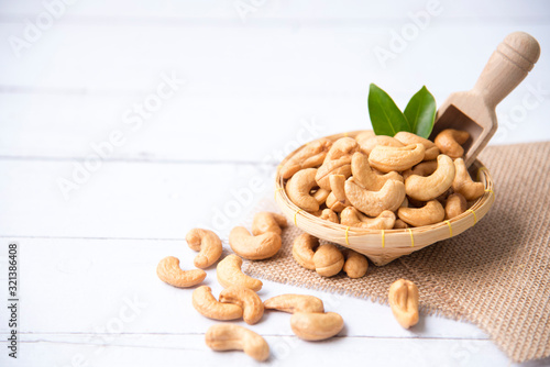Roasted salted raw cashew nuts with Fresh cashew in spoon and  basket isolated on white wooden background. photo