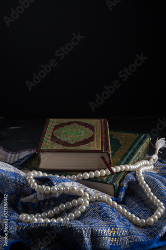 Faith in Islam, Holy book Islamic scripture al-Quran and rosary beads on dark background. Islamic holiday celebration Eid Mubarak or Ramadan Kareem concept. photo