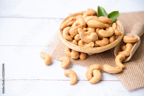 Roasted salted raw cashew nuts with Fresh cashew in spoon and  basket isolated on white wooden background.