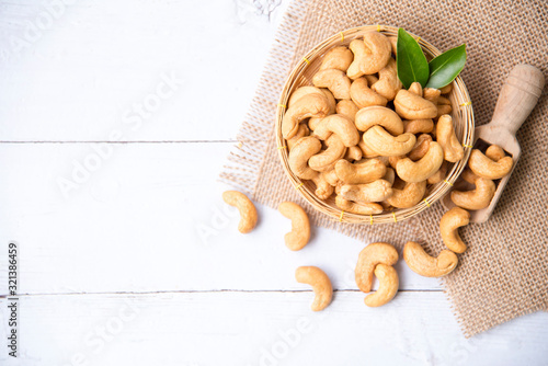 Fotografija Roasted salted raw cashew nuts with Fresh cashew in spoon and  basket isolated on white wooden background
