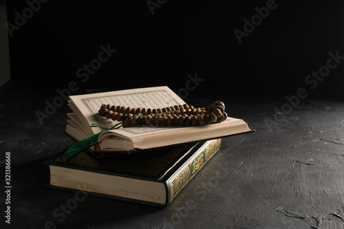 Faith in Islam, Holy book Islamic scripture al-Quran and rosary beads on dark background. Islamic holiday celebration Eid Mubarak or Ramadan Kareem concept.
