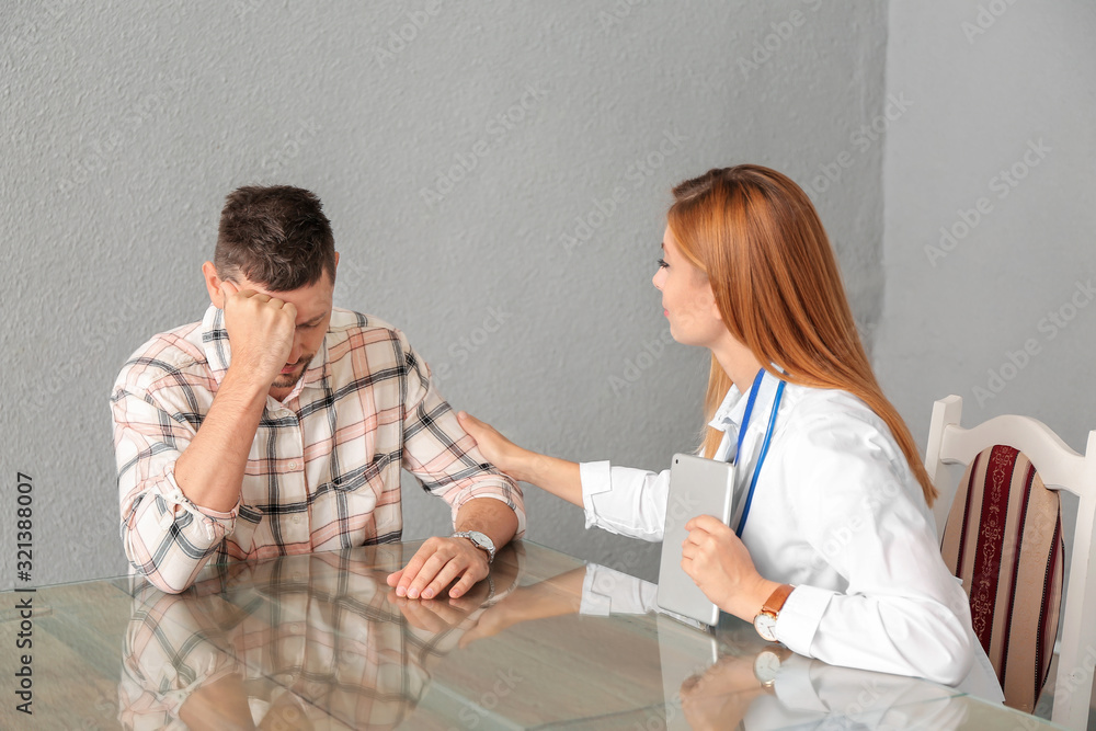 Fototapeta premium Female doctor calming sad patient in clinic