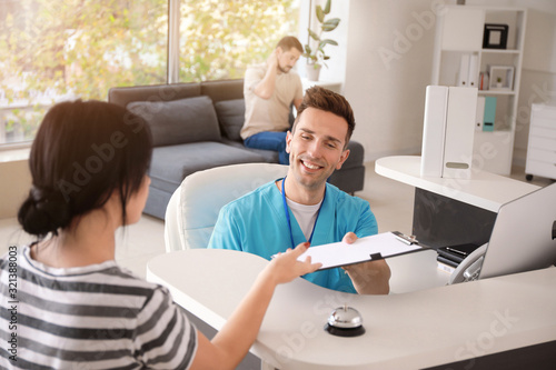 Male receptionist working with patient in clinic photo