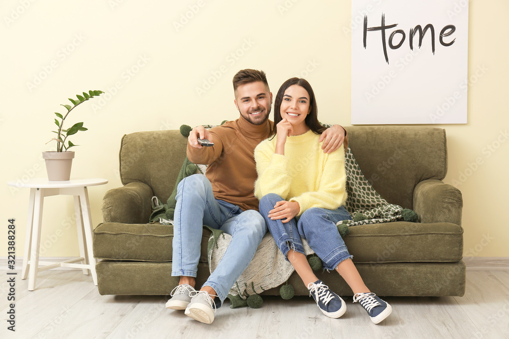 Young couple watching TV while sitting on sofa at home