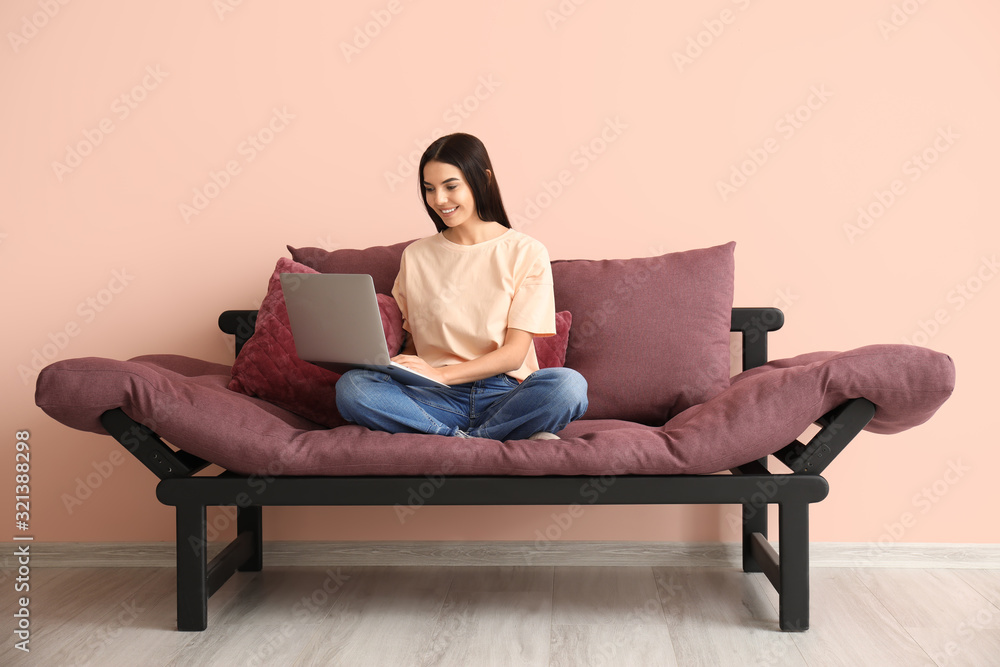 Young woman with laptop sitting on sofa at home Young woman with laptop sitting on sofa at home