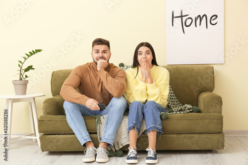 Afraid couple watching TV w...