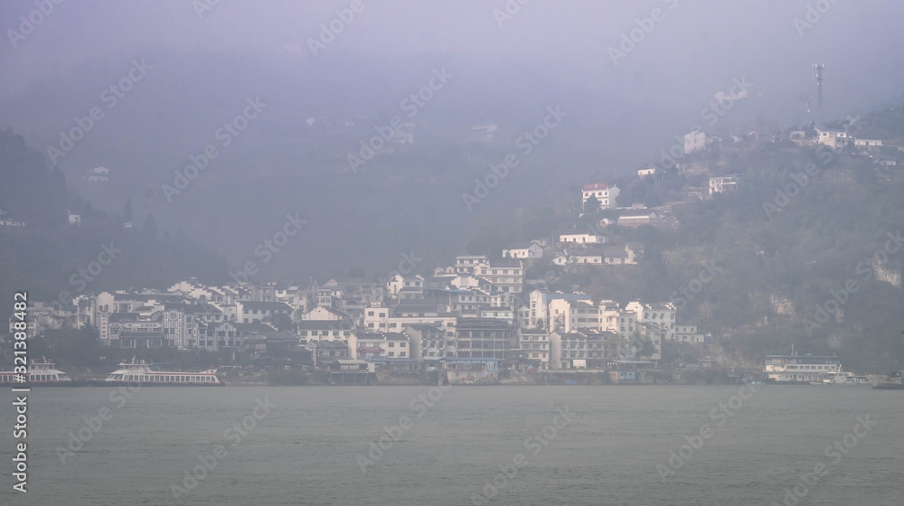 The wooden village along with the hill beside the Yangtze river in the part of Three Gorges Dam.