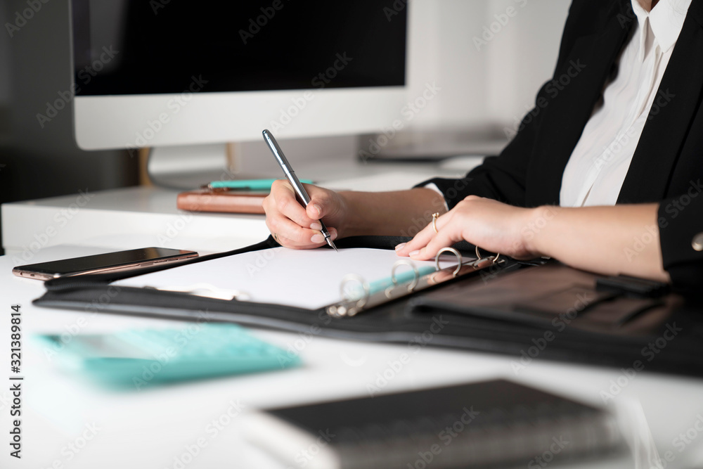 Office work. Cropped image of female employee working in office, supplies on tabletop. Office work. Cropped image of female employee working in office, supplies on tabletop.